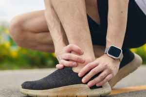 man holding ankle with both hands as if he's in pain